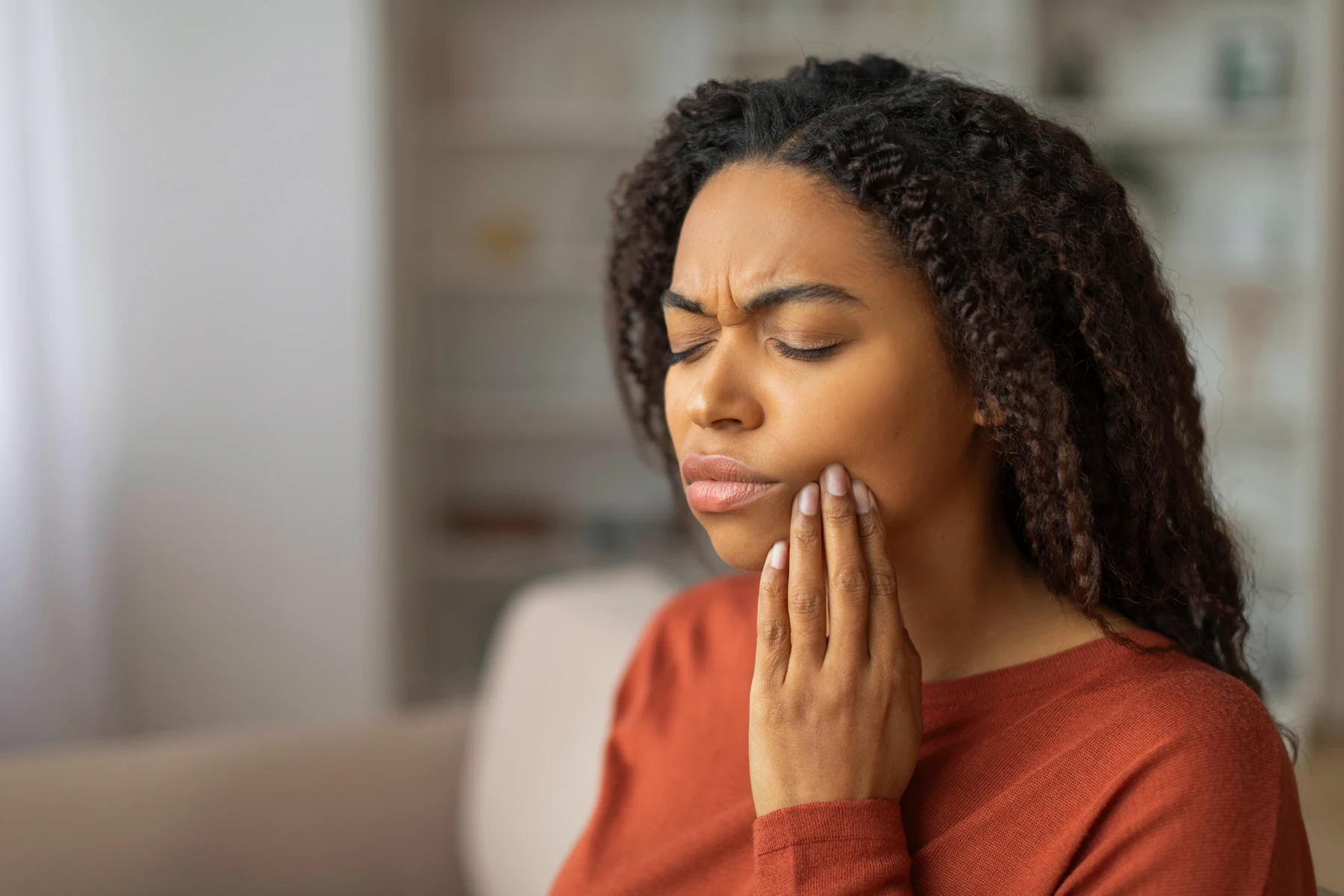 A patient holding her cheek because of dental pain